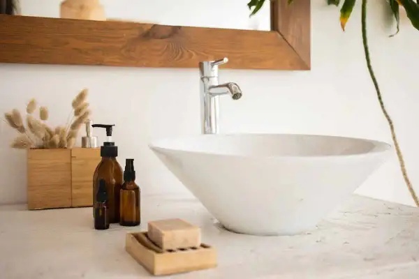 Un lavandino che perde, con flaconi ambrati e sapone in un portasapone di legno.