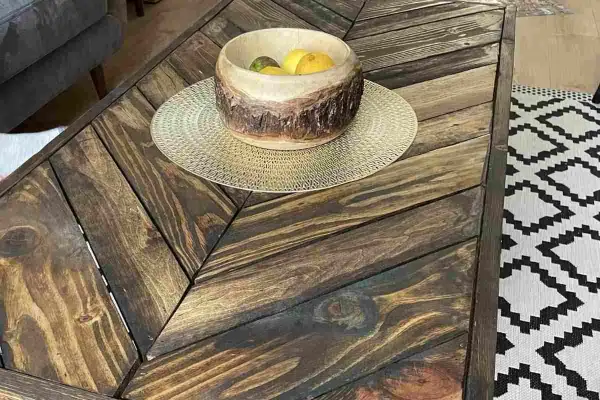Tavolino con pallet fai da te, con ciotola di frutta e tappeto geometrico.