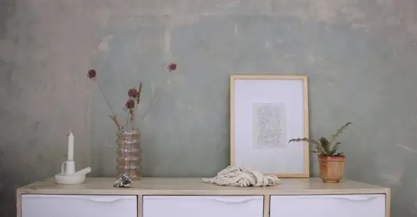 Parete con effetto materico, ideale per chi vuole imparare come pitturare una parete con stile. Arredamento minimalista con vasi, candela e quadro.